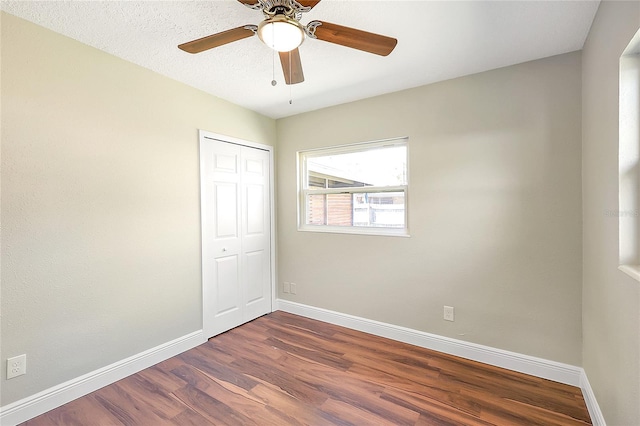 spare room with dark wood finished floors, a ceiling fan, and baseboards