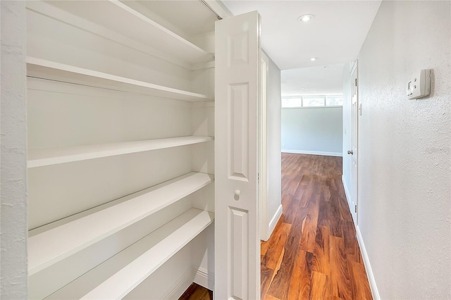 hallway featuring recessed lighting, baseboards, and wood finished floors