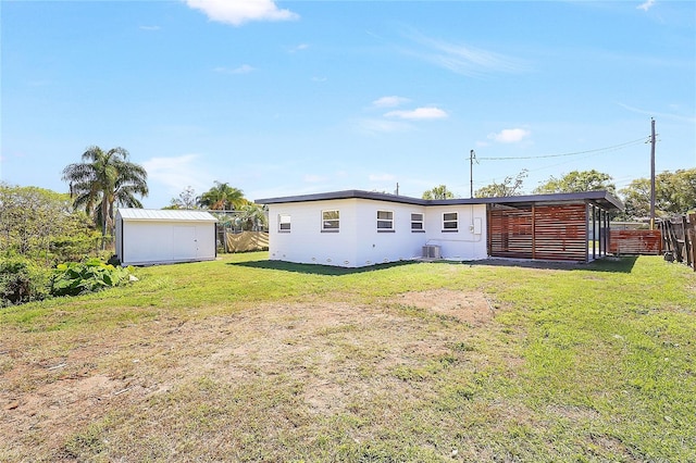 back of property with central AC unit, fence, a shed, an outdoor structure, and a lawn