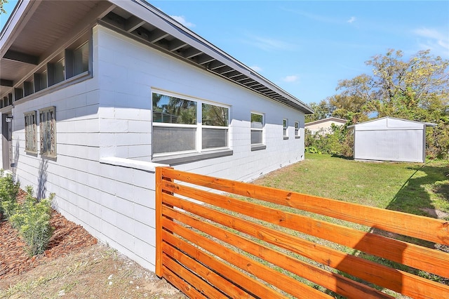 view of home's exterior with a lawn, an outdoor structure, and a storage shed