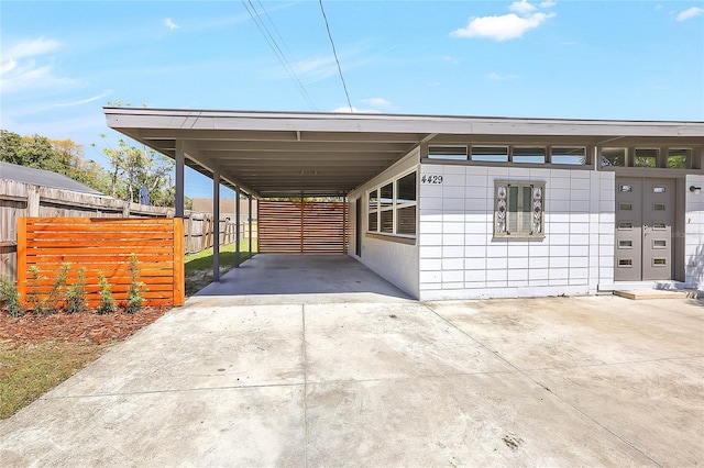 view of car parking with an attached carport, fence, and driveway