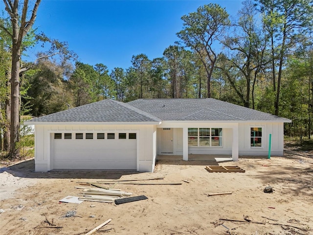 ranch-style house featuring driveway, board and batten siding, roof with shingles, and an attached garage