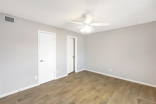 spare room with visible vents, a textured ceiling, baseboards, and wood finished floors