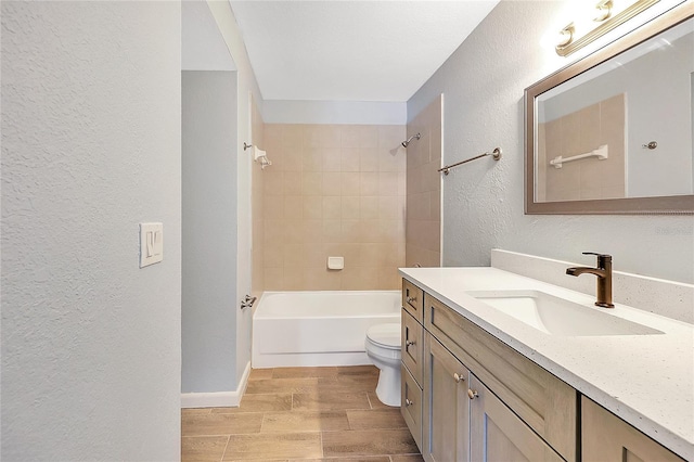 full bath with wood finish floors, toilet, bathing tub / shower combination, vanity, and a textured wall