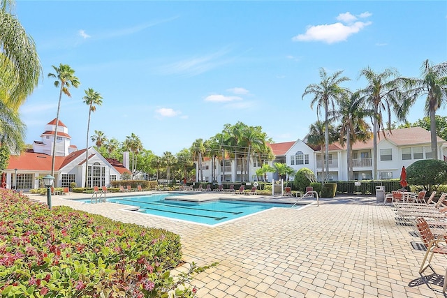 community pool with a residential view, a patio, and fence