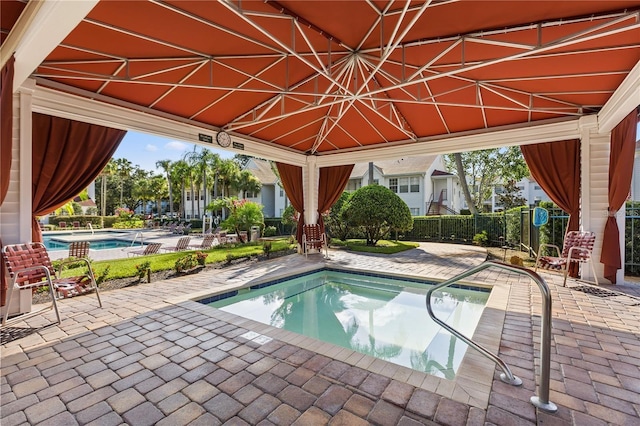 community pool with a gazebo, fence, and a patio area