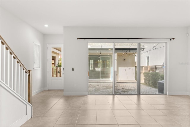 tiled spare room featuring a wealth of natural light, stairs, and baseboards