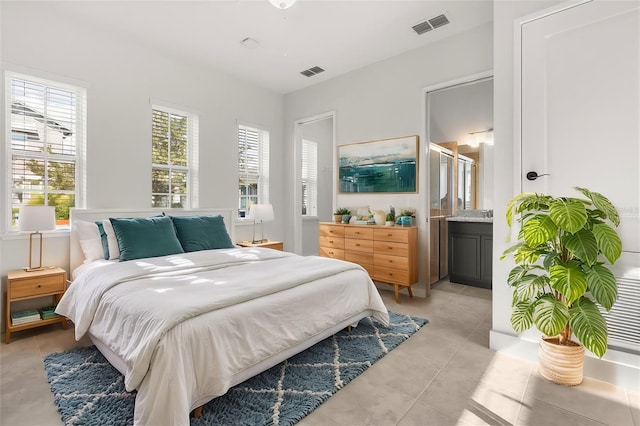 bedroom with connected bathroom, visible vents, and light tile patterned flooring