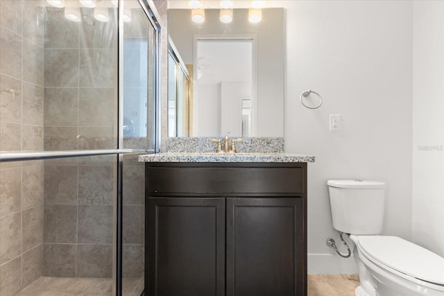 bathroom with toilet, a stall shower, and vanity