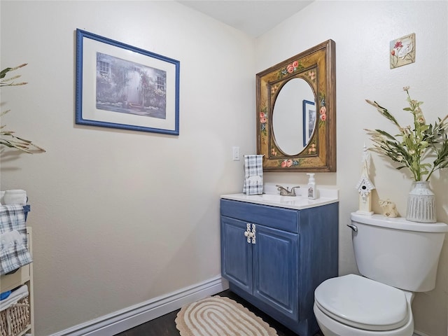 bathroom with toilet, vanity, and baseboards