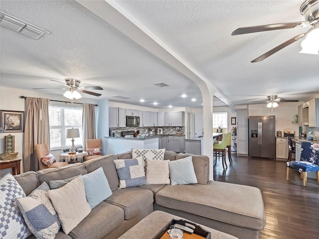 living area featuring dark wood-type flooring, a ceiling fan, and visible vents