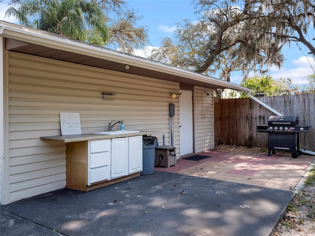 view of patio / terrace featuring a sink, grilling area, an outdoor kitchen, and fence