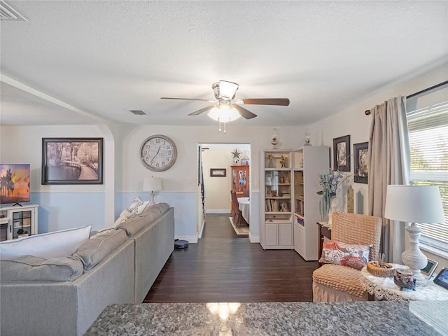 living room featuring visible vents, a textured ceiling, ceiling fan, and wood finished floors