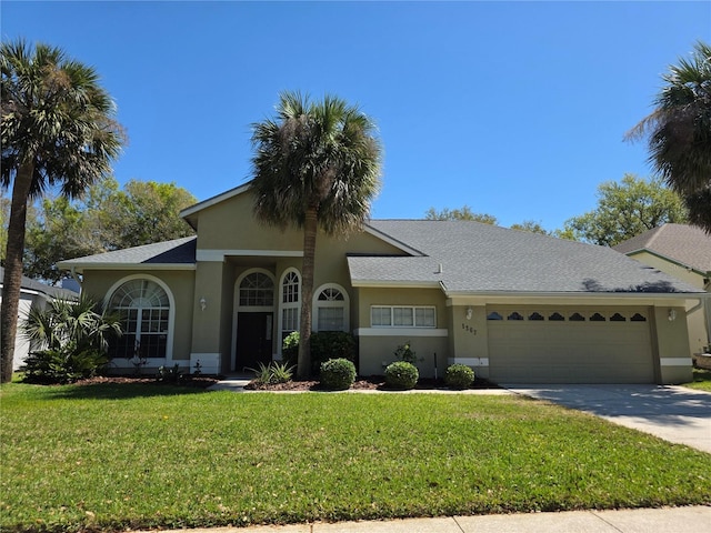 ranch-style home featuring stucco siding, a front yard, a garage, and driveway