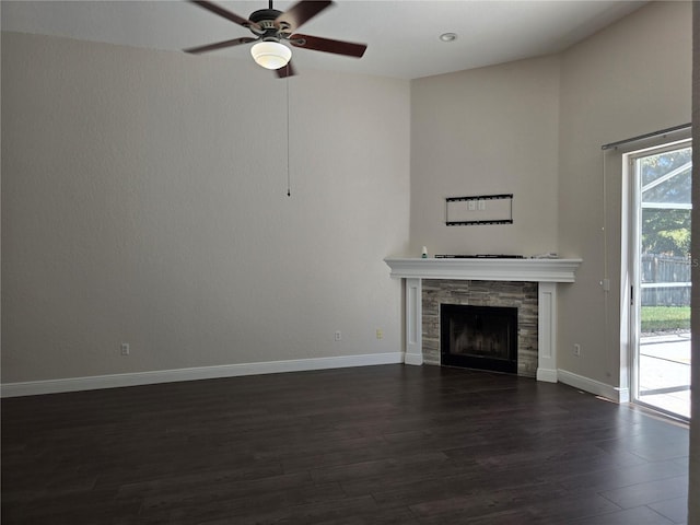 unfurnished living room with baseboards, dark wood-type flooring, a ceiling fan, and a tile fireplace