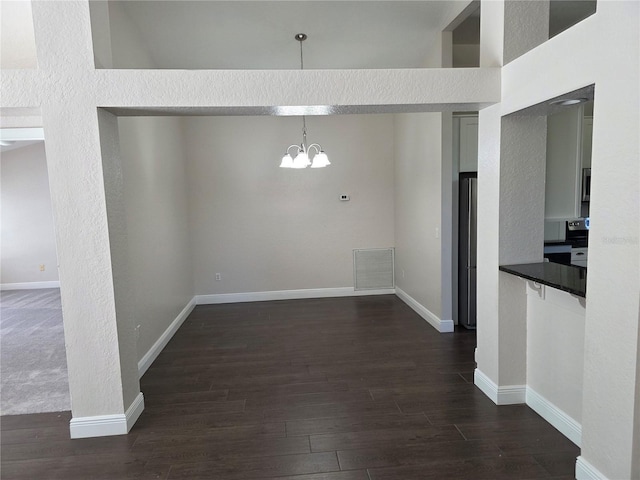 unfurnished dining area featuring an inviting chandelier, dark wood-type flooring, baseboards, and visible vents