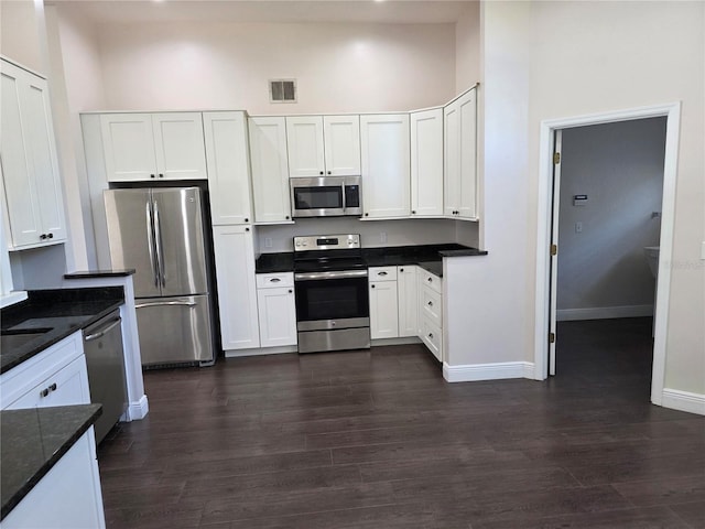 kitchen featuring visible vents, dark wood finished floors, appliances with stainless steel finishes, white cabinets, and baseboards