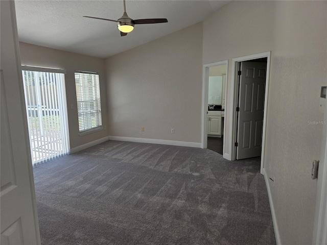 interior space with access to outside, connected bathroom, dark colored carpet, baseboards, and vaulted ceiling