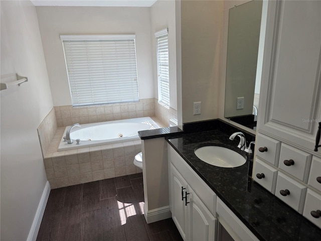 full bath featuring a jetted tub, vanity, and wood finished floors