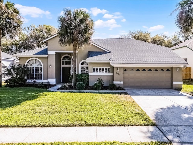 view of front of home featuring a front yard, an attached garage, a shingled roof, stucco siding, and concrete driveway