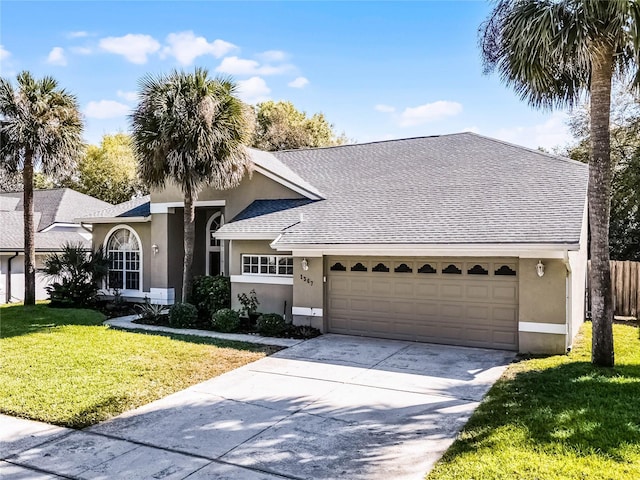 view of front of property featuring stucco siding, roof with shingles, concrete driveway, a front yard, and a garage