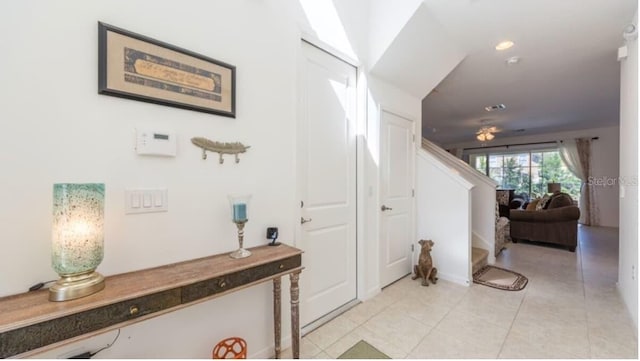 hall featuring light tile patterned flooring and stairway