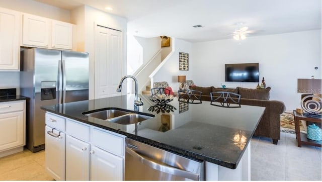 4507 Monado Dr, Kissimmee, FL 34746 - kitchen featuring dark stone countertops, a center island with sink, a sink, appliances with stainless steel finishes, and white cabinetry