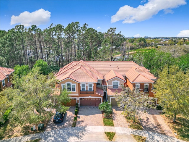 view of front of property featuring decorative driveway, a tile roof, an attached garage, and stucco siding