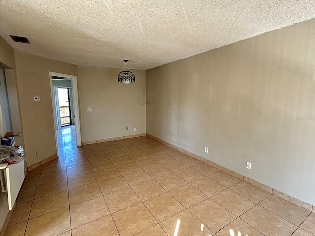 empty room featuring light tile patterned floors, visible vents, baseboards, and a textured ceiling