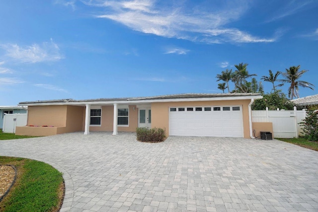 ranch-style house featuring stucco siding, an attached garage, decorative driveway, and fence