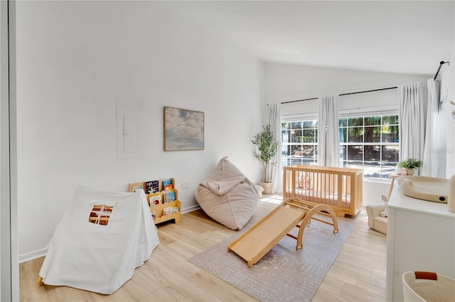 bedroom with light wood-type flooring, lofted ceiling, and baseboards