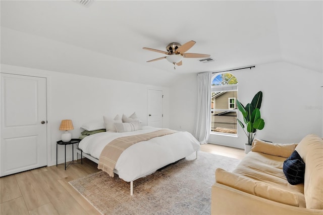 bedroom featuring visible vents, light wood-style flooring, a ceiling fan, and lofted ceiling