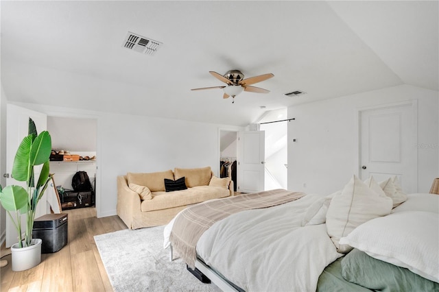 bedroom featuring light wood finished floors, visible vents, a ceiling fan, and vaulted ceiling