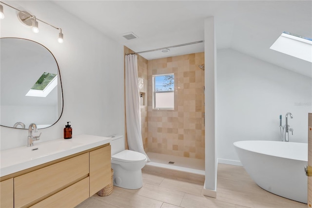 bathroom featuring vanity, visible vents, vaulted ceiling with skylight, a tile shower, and toilet