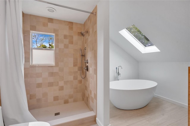 full bathroom featuring a soaking tub, vaulted ceiling with skylight, baseboards, and tiled shower