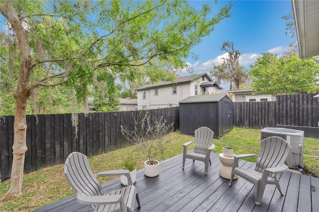 wooden terrace featuring an outdoor structure, cooling unit, a fenced backyard, and a shed