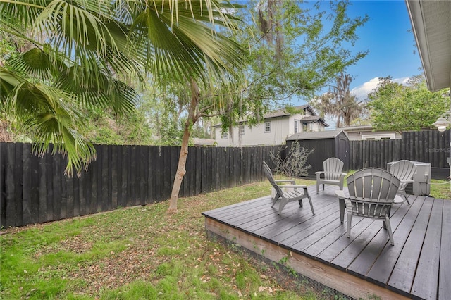 deck featuring an outbuilding, a fenced backyard, and a storage shed