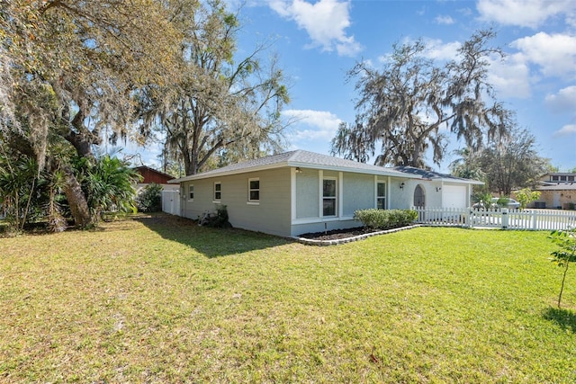 rear view of property featuring a yard, fence private yard, an attached garage, and stucco siding