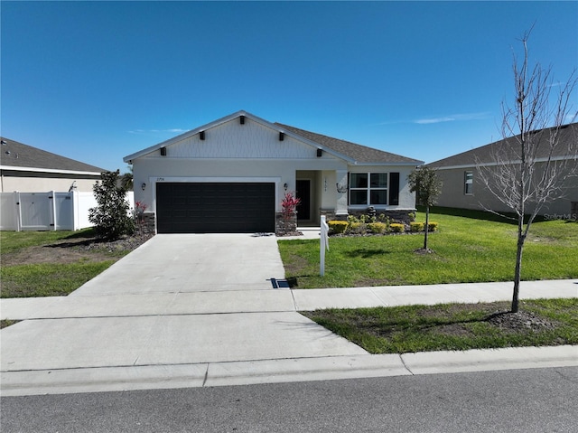 view of front of home with a front yard, a gate, fence, an attached garage, and concrete driveway