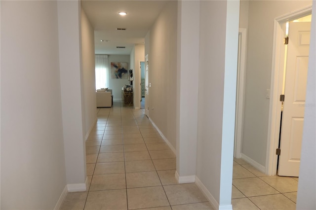 corridor featuring light tile patterned floors, visible vents, and baseboards