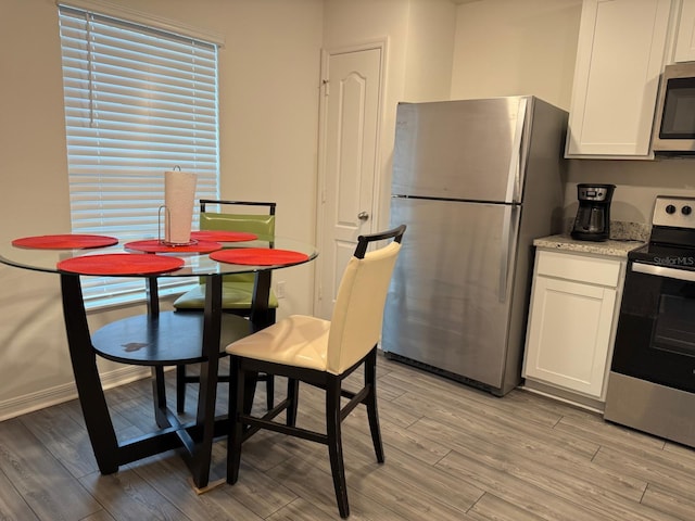 dining room featuring light wood-type flooring and baseboards