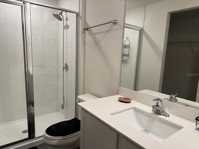 bathroom featuring vanity, a shower stall, and toilet