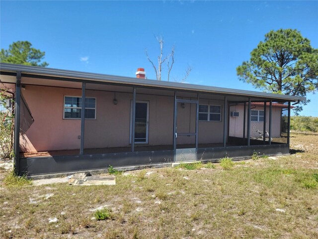 rear view of property with a yard, a sunroom, and stucco siding