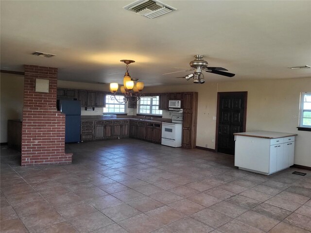 kitchen featuring white appliances, decorative light fixtures, and visible vents