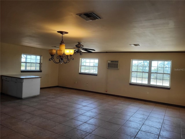 spare room with a chandelier, visible vents, a wall mounted air conditioner, and baseboards