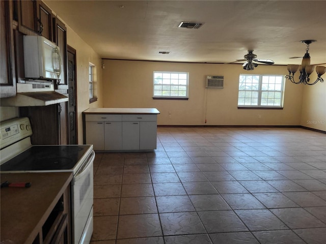 kitchen with white appliances, an AC wall unit, visible vents, and a wealth of natural light