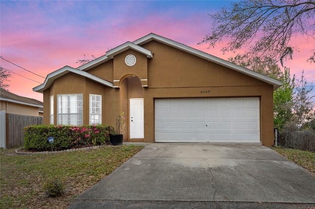 single story home featuring concrete driveway, an attached garage, fence, and stucco siding