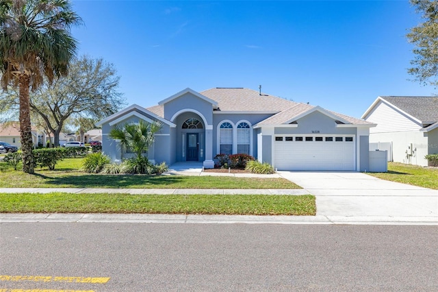 view of front of house with stucco siding, driveway, a front yard, and a garage