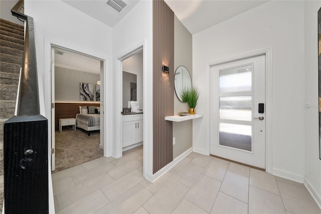 entryway featuring visible vents, light carpet, light tile patterned floors, baseboards, and stairs