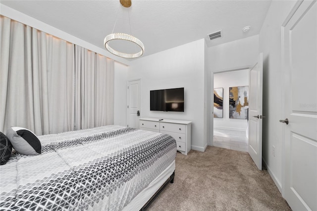 bedroom with visible vents, light colored carpet, a textured ceiling, and baseboards